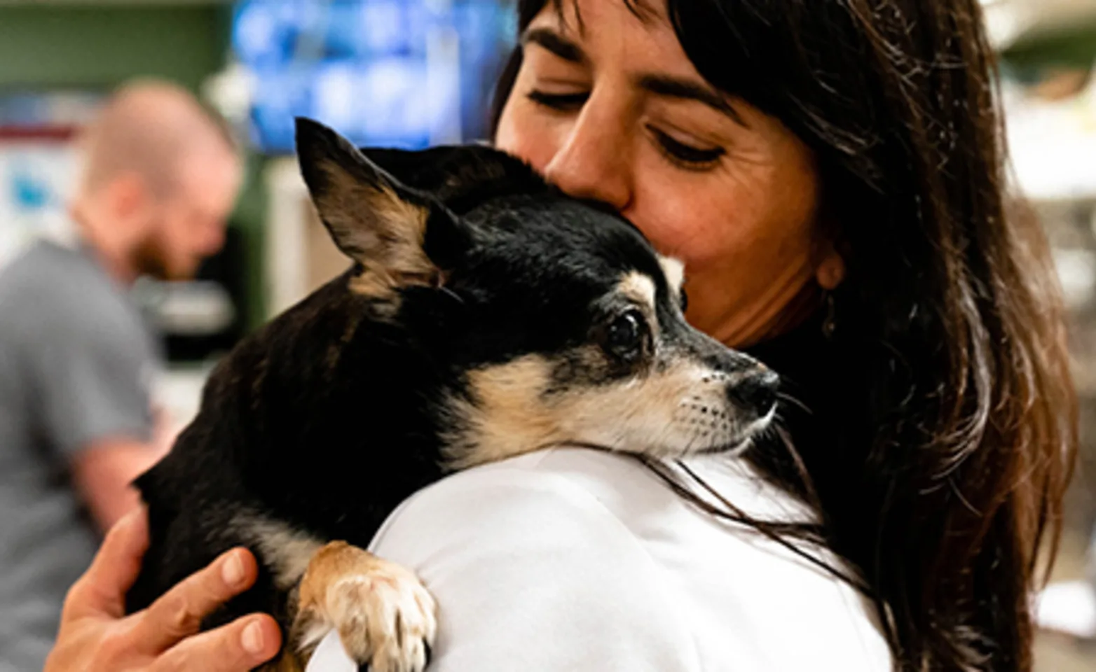Veterinarian holding and kissing small black dog